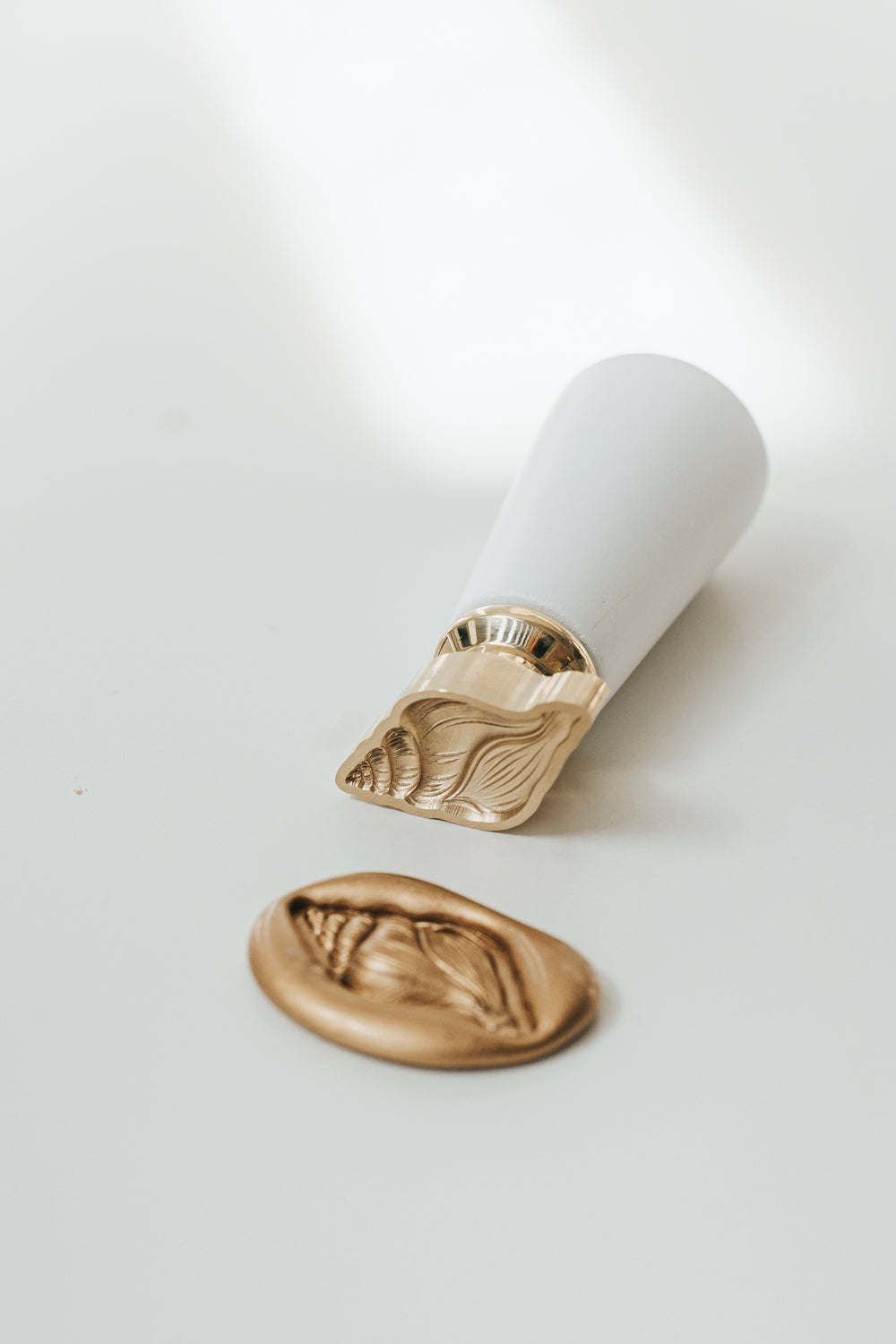 Brass Conch wax seal stamp with matching gold wax seal impression featuring a detailed seashell design.