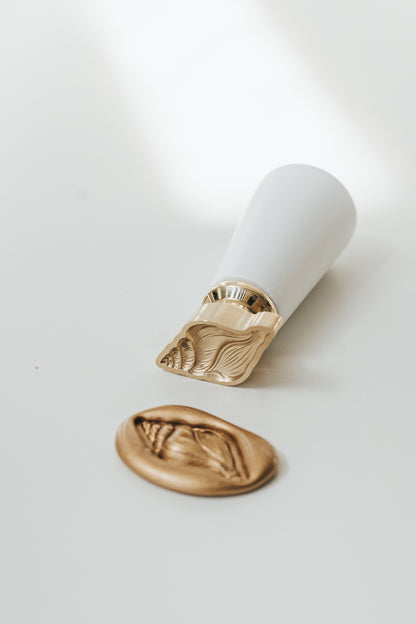 Brass Conch wax seal stamp with matching gold wax seal impression featuring a detailed seashell design.