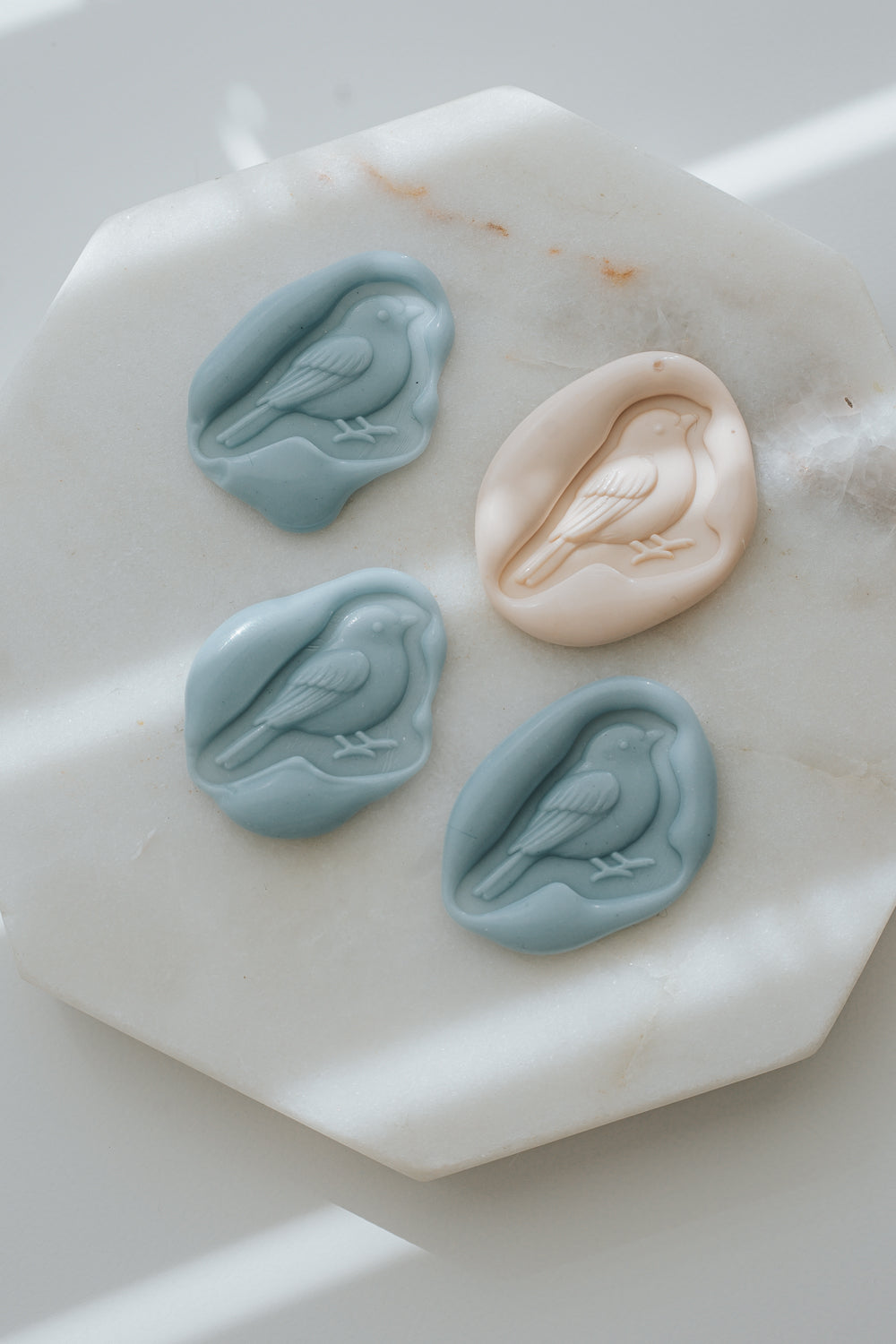 Dusty Blue and sakura songbird wax seals on marble background