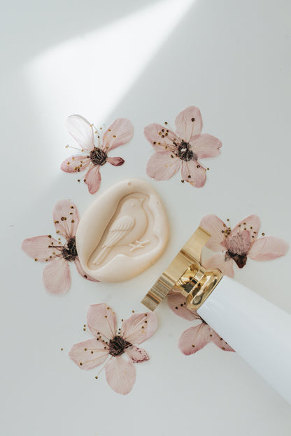 Songbird wax seal impression with sakura wax and cherry blossoms in the background