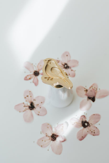 Songbird wax seal stamp with brass head and cherry blossom petals in the background