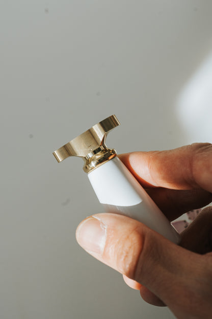 Close-up of the brass wax seal stamp with white handle held in hand 