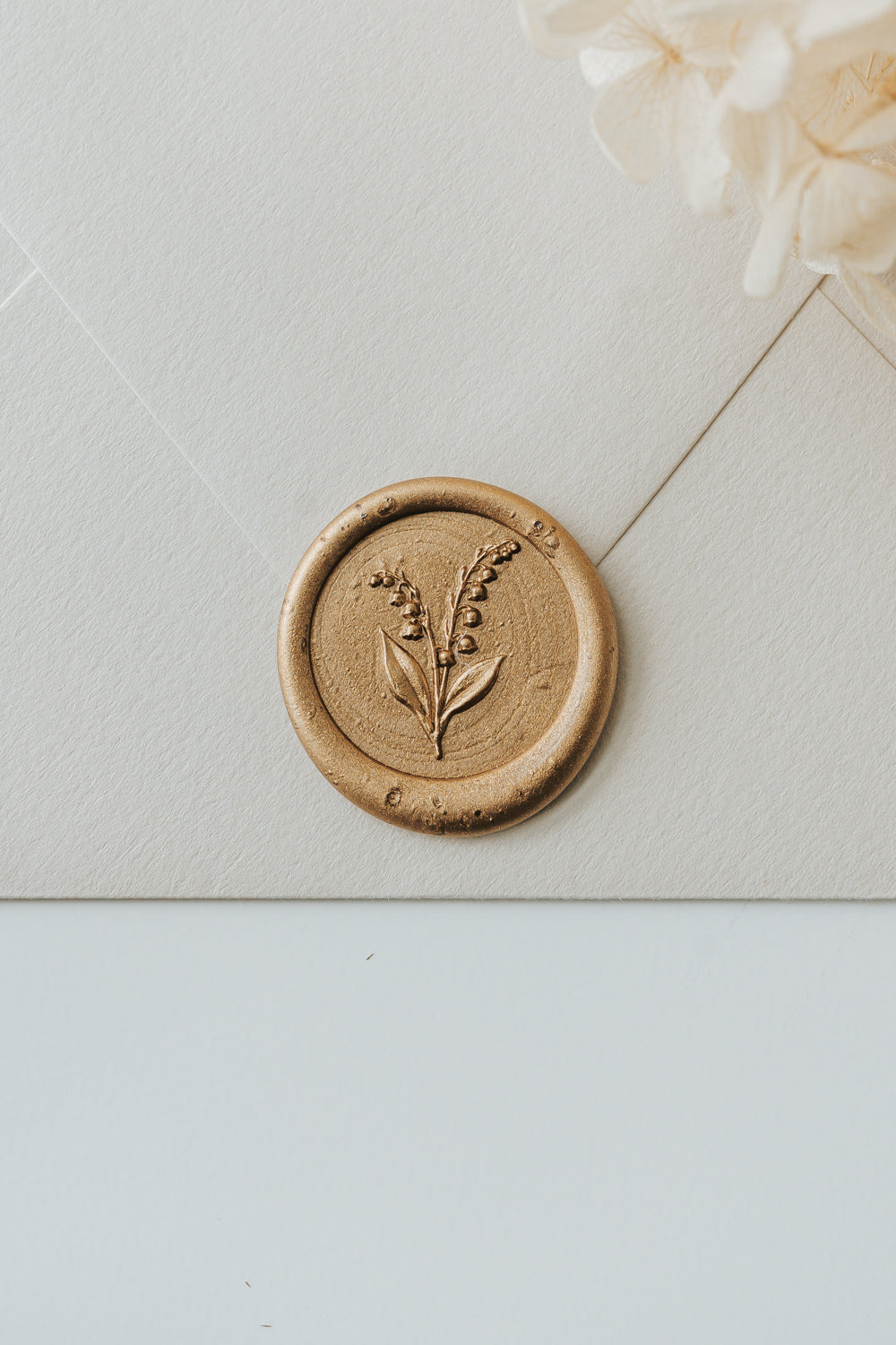 Lily of the valley wax seal with gold sealing wax on textured envelope for elegant mail styling