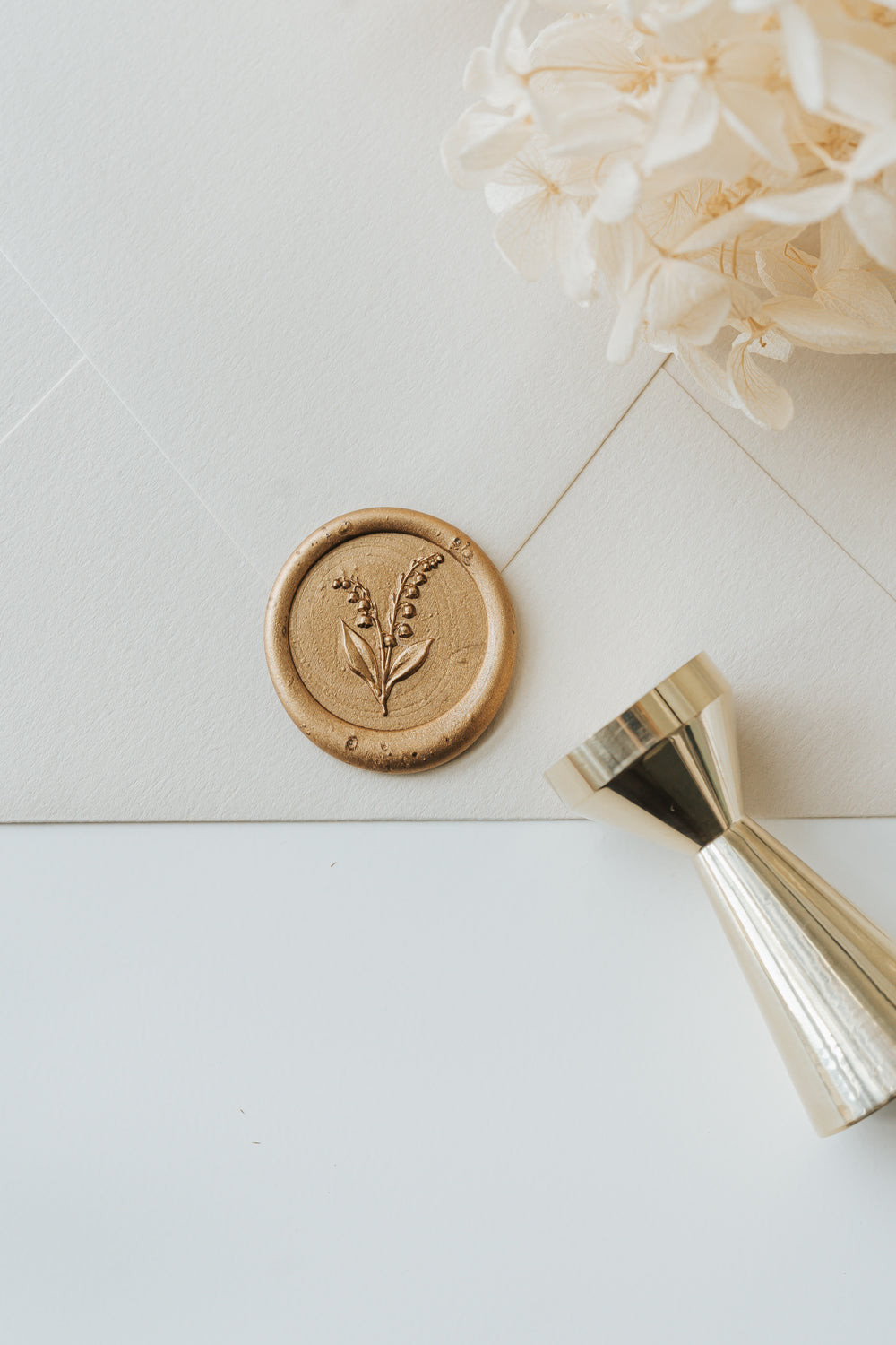 Lily of the valley wax seal on cream envelope with brass wax seal stamp and gold sealing wax