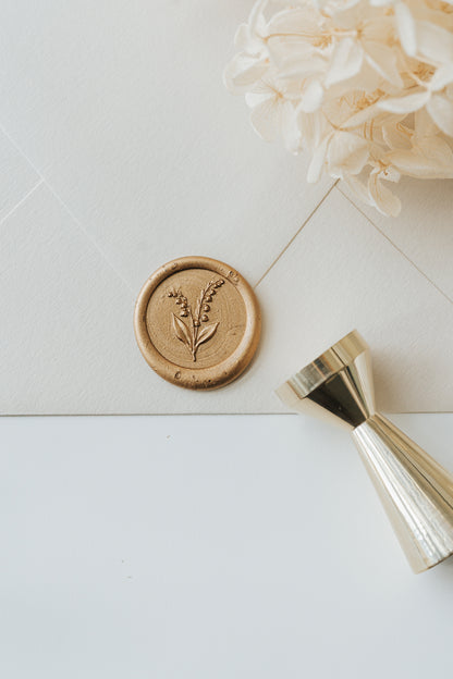 Lily of the valley wax seal on cream envelope with brass wax seal stamp and gold sealing wax