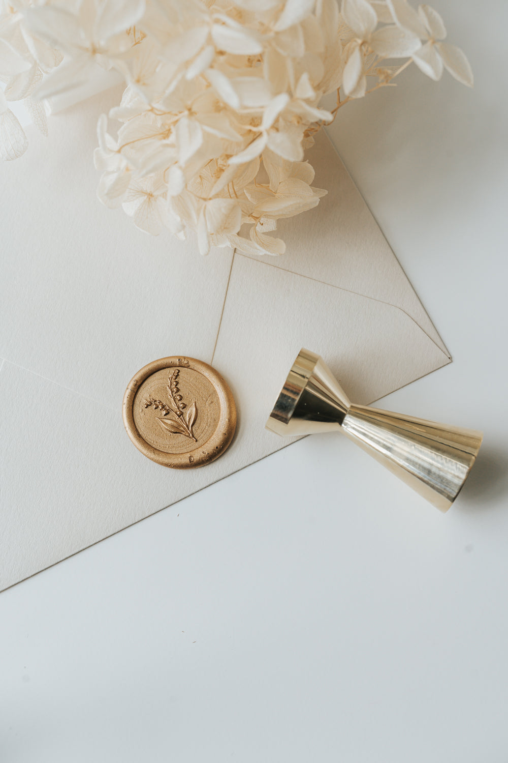 Gold lily of the valley wax seal for wedding invitations with brass melting spoon and envelopes