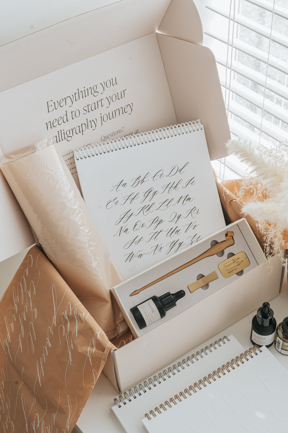 Calligraphy starter kit gift set with worksheets, pen, ink, and packaging in neutral aesthetic