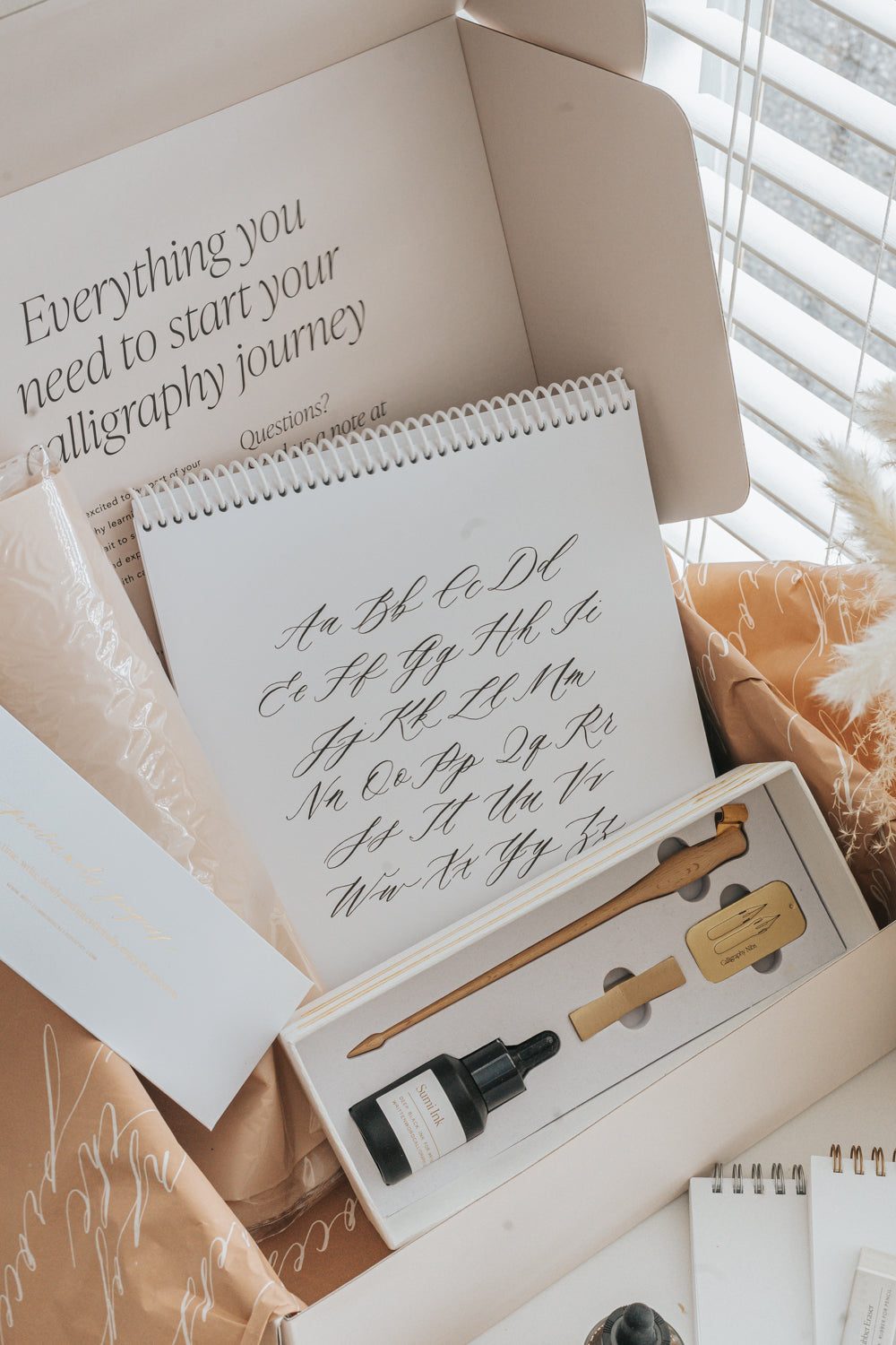 Beginner calligraphy kit with alphabet worksheets, pen holder, nibs, and ink set on desk