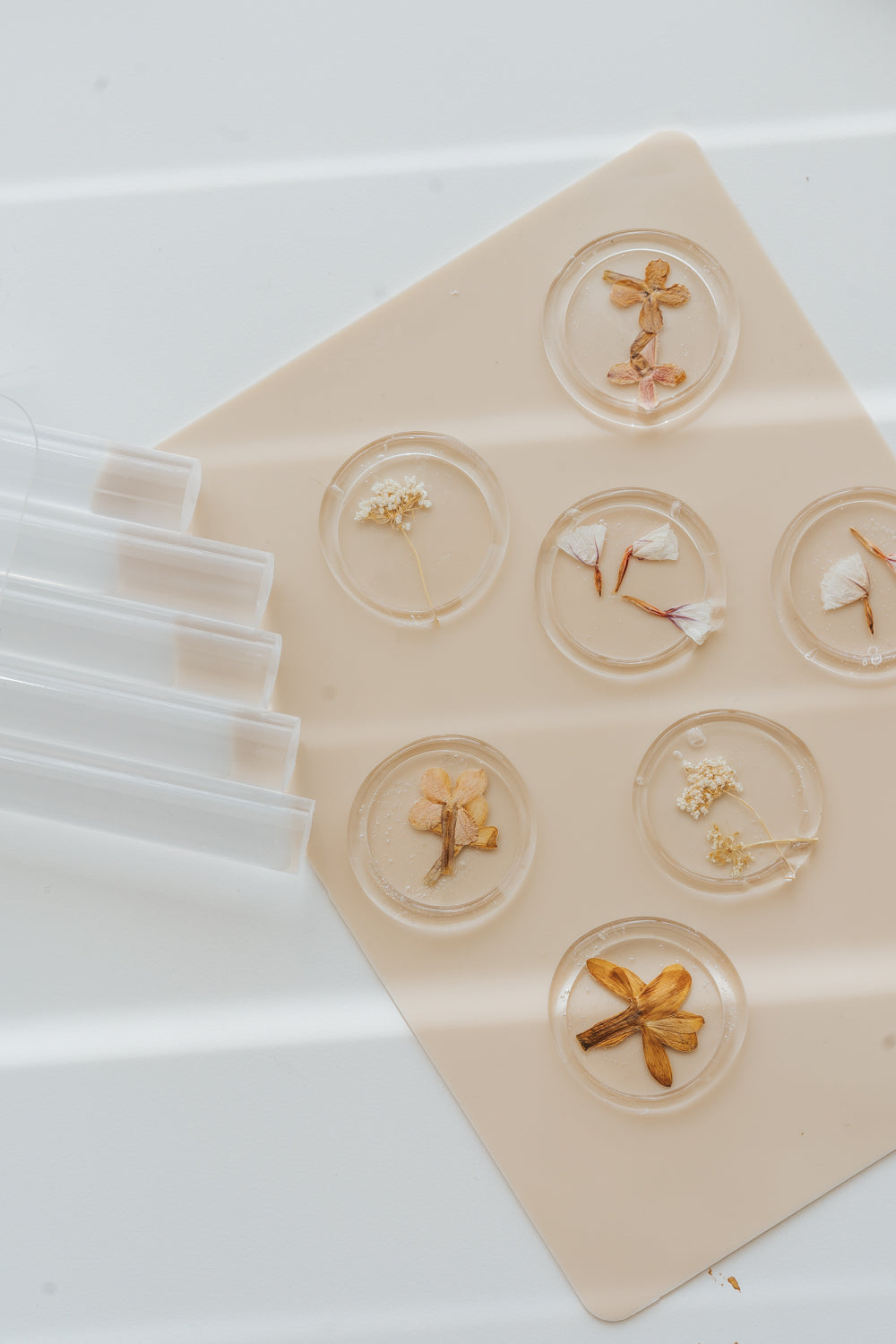 Clear wax seals with pressed flowers arranged on silicone mat with glue sticks