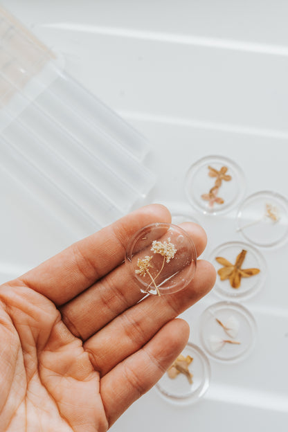 Hand holding clear wax seal with dried flower embedded inside
