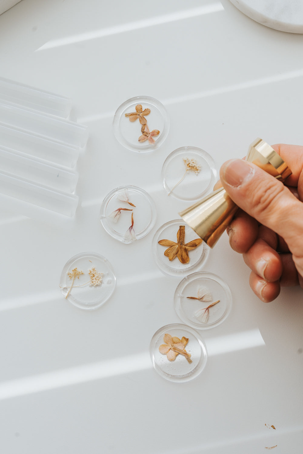 Clear wax seals with dried florals and brass stamp on white surface