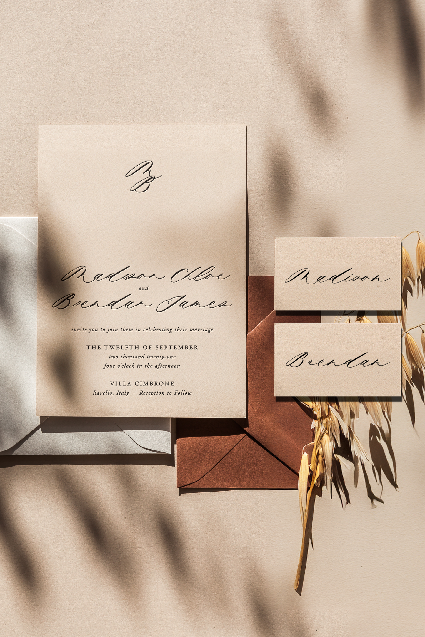 Wedding invitation suite featuring Mycella calligraphy font on beige stationery with brown envelopes and dried floral accents
