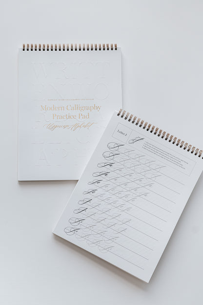 Two modern calligraphy practice pads with letters and examples for beginners, with spiral binding and gold accents