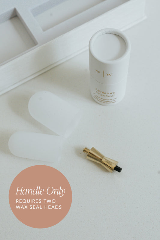 White cylindrical container next to a gold mini wax seal handle on a light surface, with text indicating 'Handle Only' and 'Requires Two Wax Seal Heads'.