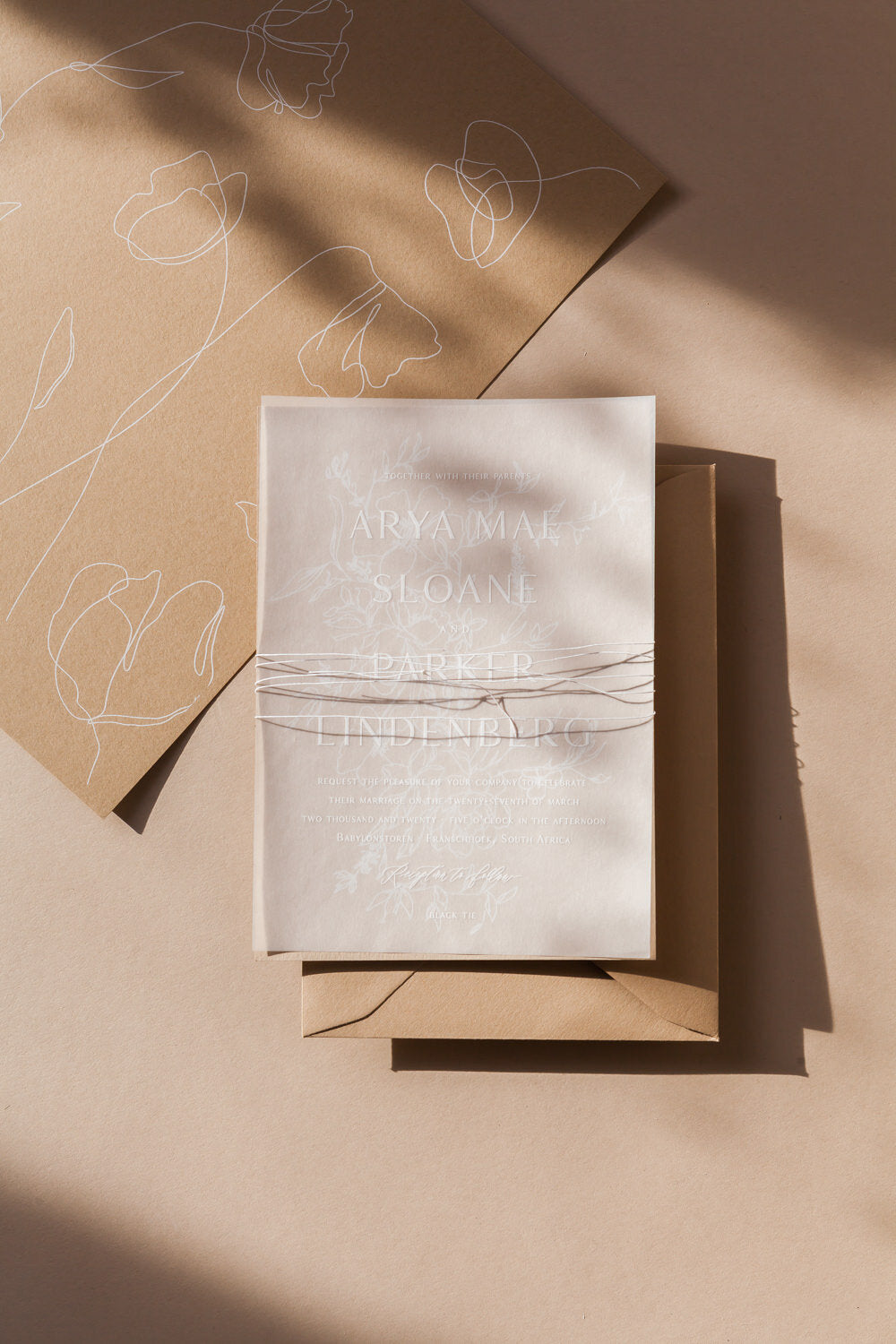 Minimalist wedding invitation with vellum overlay, soft floral line art and modern calligraphy on neutral stationery