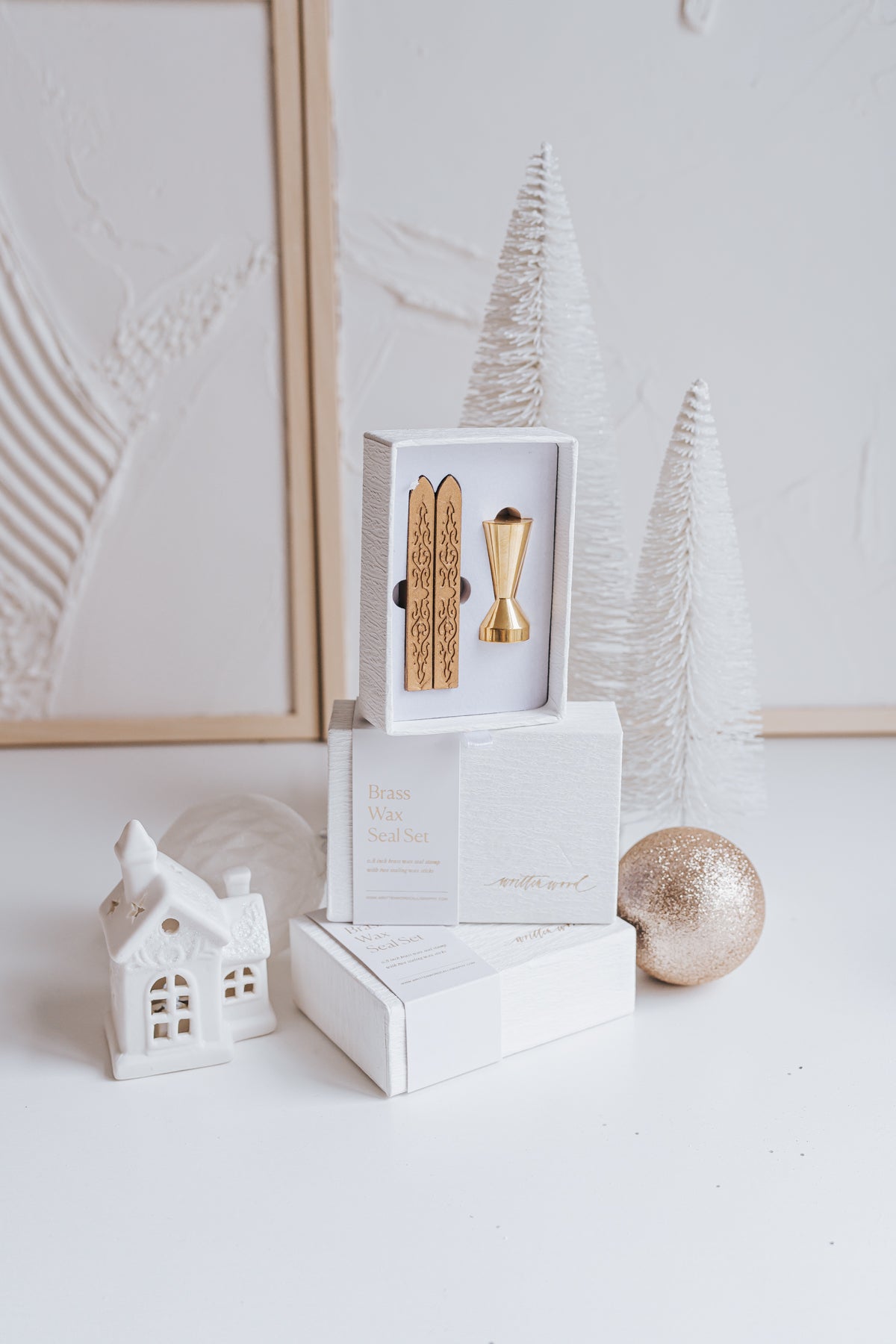 Elegant brass wax seal set with two gold wax sticks in luxury packaging, styled with holiday decor in a winter-themed setting