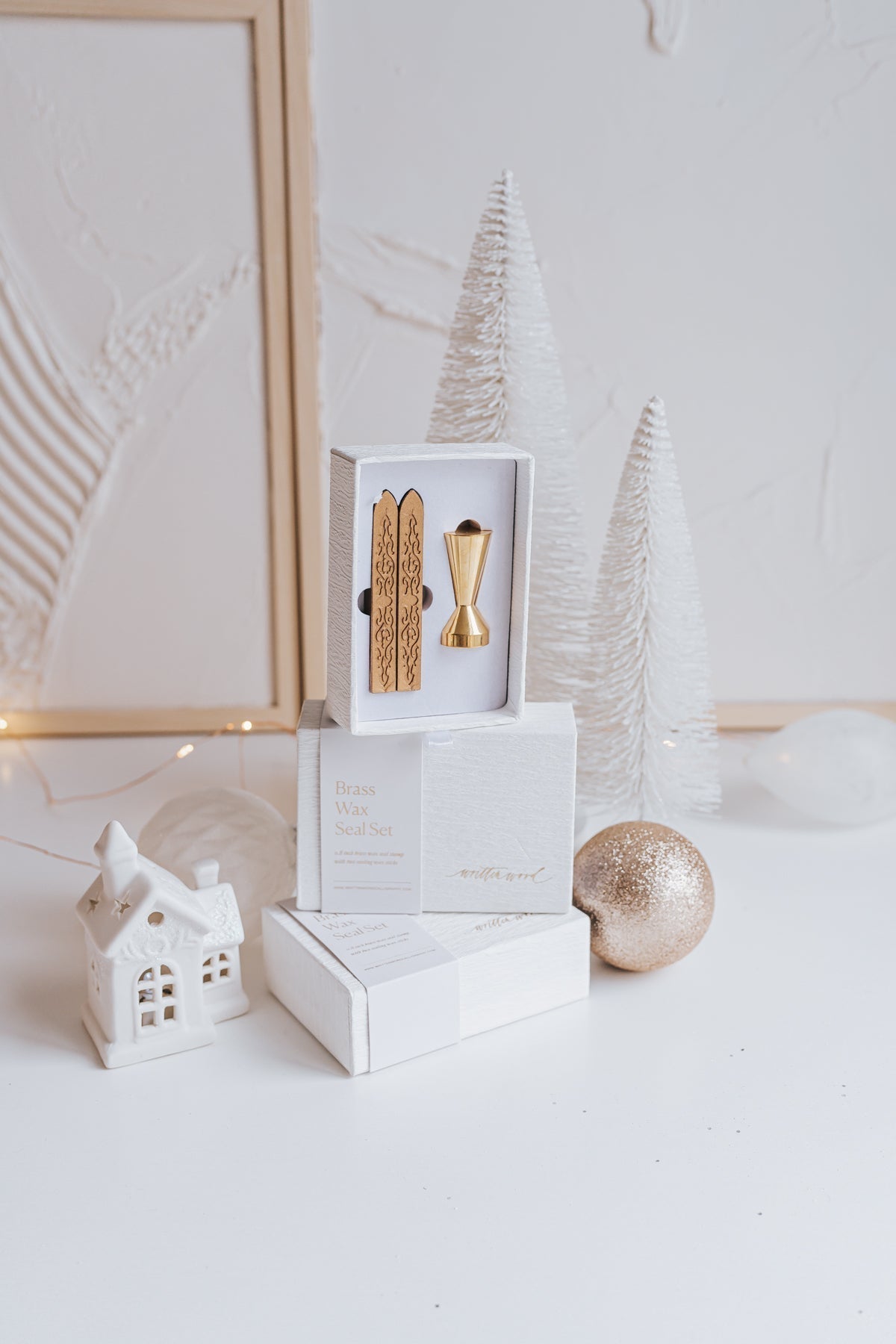 Elegant brass wax seal set with two gold wax sticks in luxury packaging, styled with holiday decor in a winter-themed setting