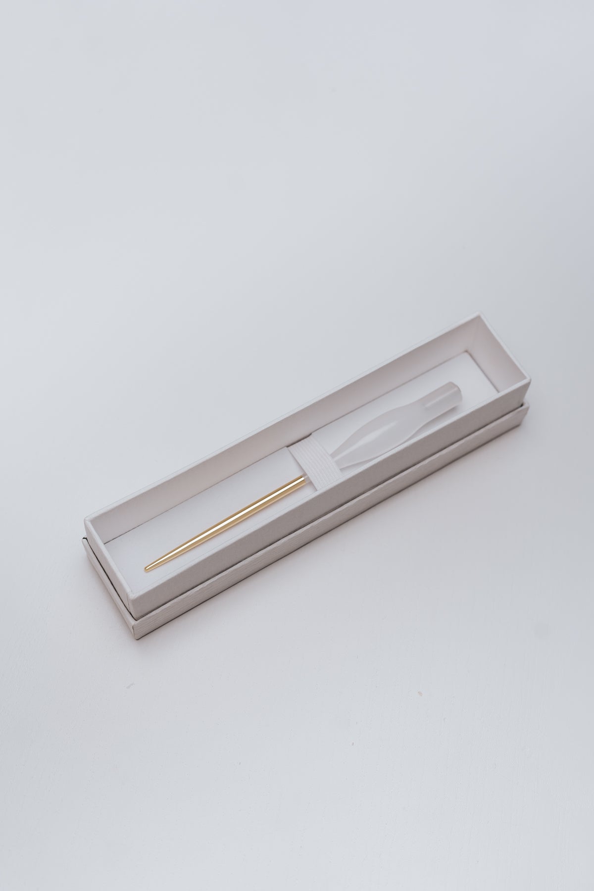 A white quartz resin straight pen with a gold brass tail, neatly packaged in a white gift box