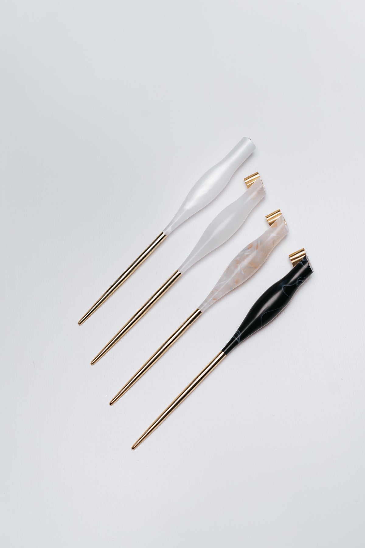 Four calligraphy pens with gold metal tails in white, rose, and black colored quartz