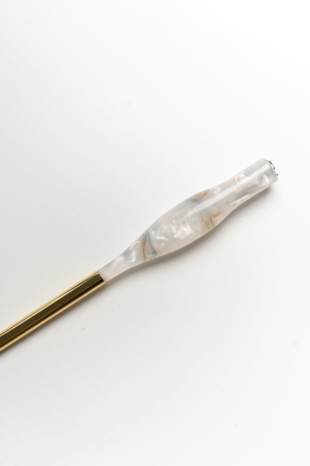 Close-up of a handmade calligraphy pen in rose quartz resin with a brass gold tail