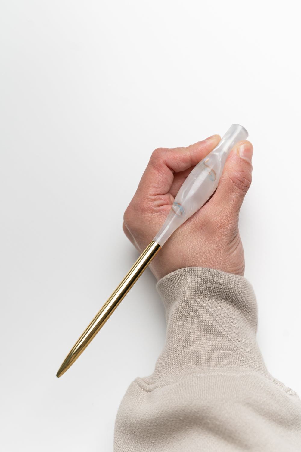 Hand holding a handmade calligraphy pen in rose quartz resin with a brass gold tail