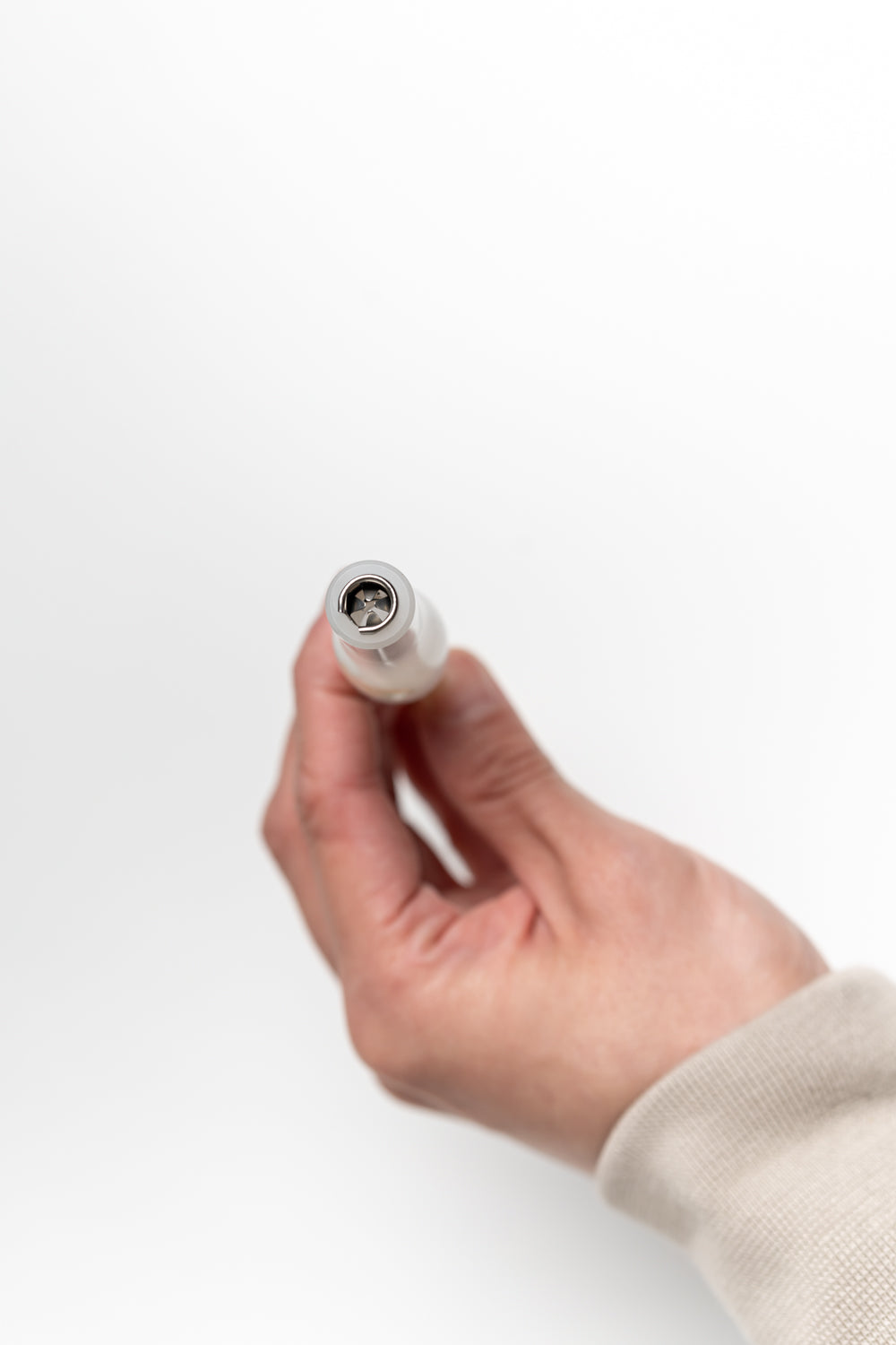 Hand holding the end of a handmade calligraphy pen, showing a four-pronged steel flange