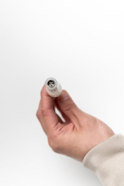 Hand holding the end of a handmade calligraphy pen, showing a four-pronged steel flange