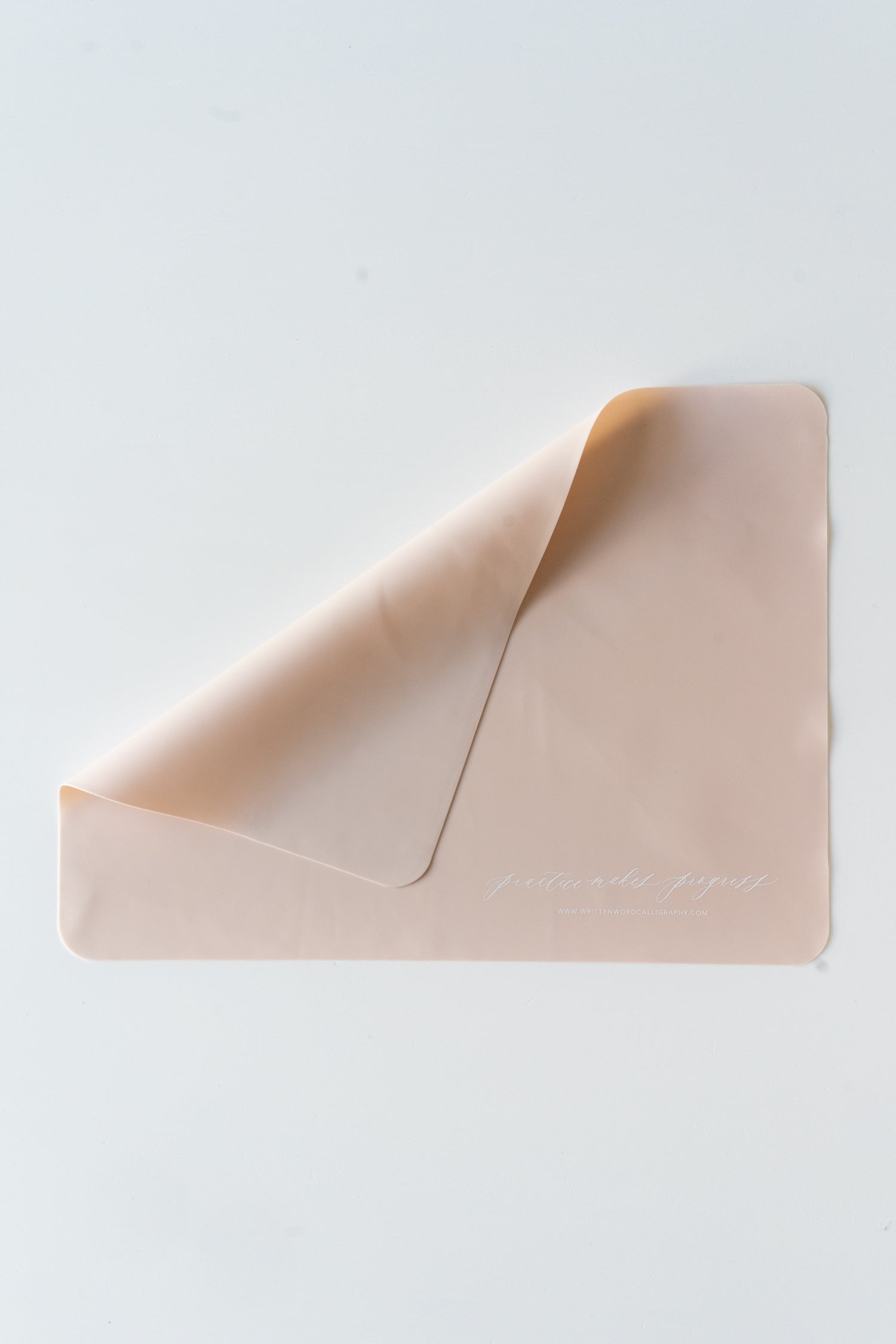 A pink silicone practice mat with the words 'practice makes progress' at the bottom in white