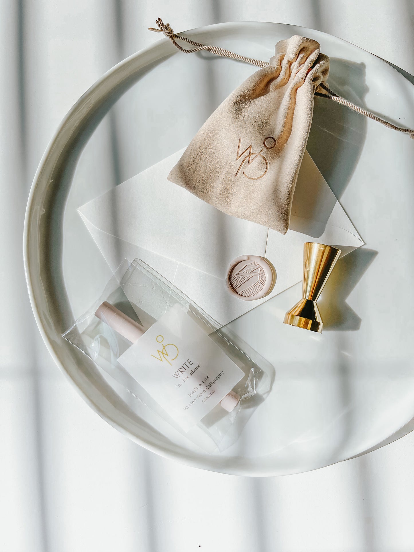 Sand dunes wax seal stamp with a blush wax seal on an envelope, gold brass stamp, and sealing wax set, styled on a white tray
