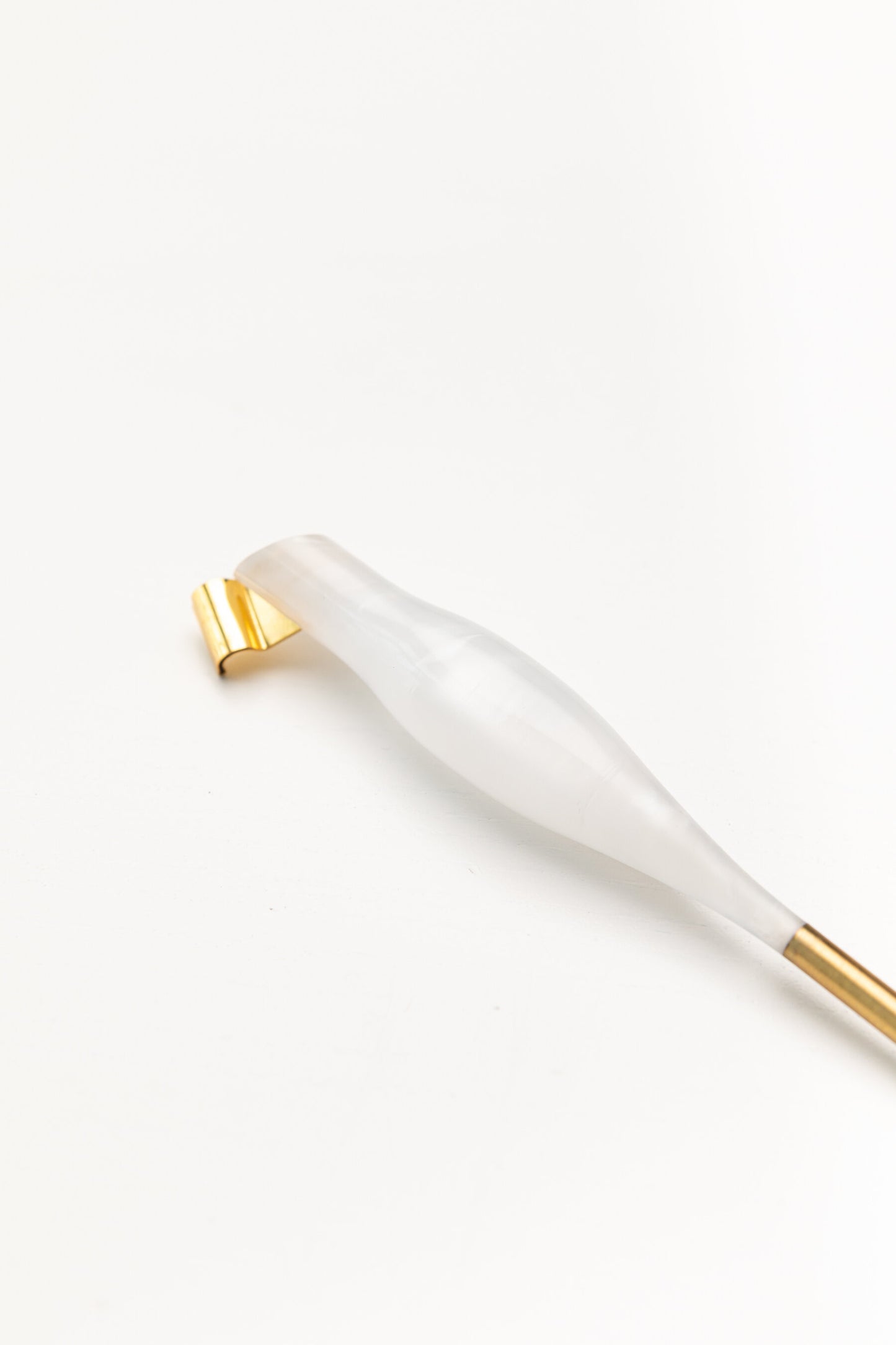 Close-up of a pearl-toned oblique calligraphy pen with a sleek design and a gold brass flange, placed on a white background