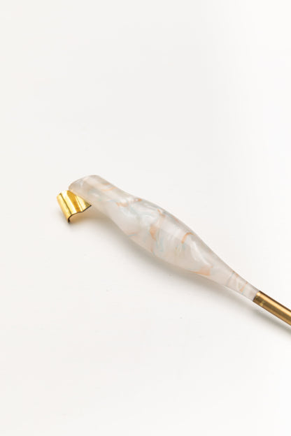 Close-up of a swirled pearl and gold oblique calligraphy pen featuring a gold brass flange, placed on a minimalist white background