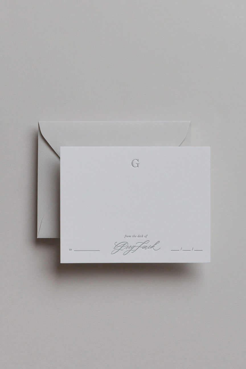 Personalized stationery card with embossed initial and calligraphy name on minimalist neutral background