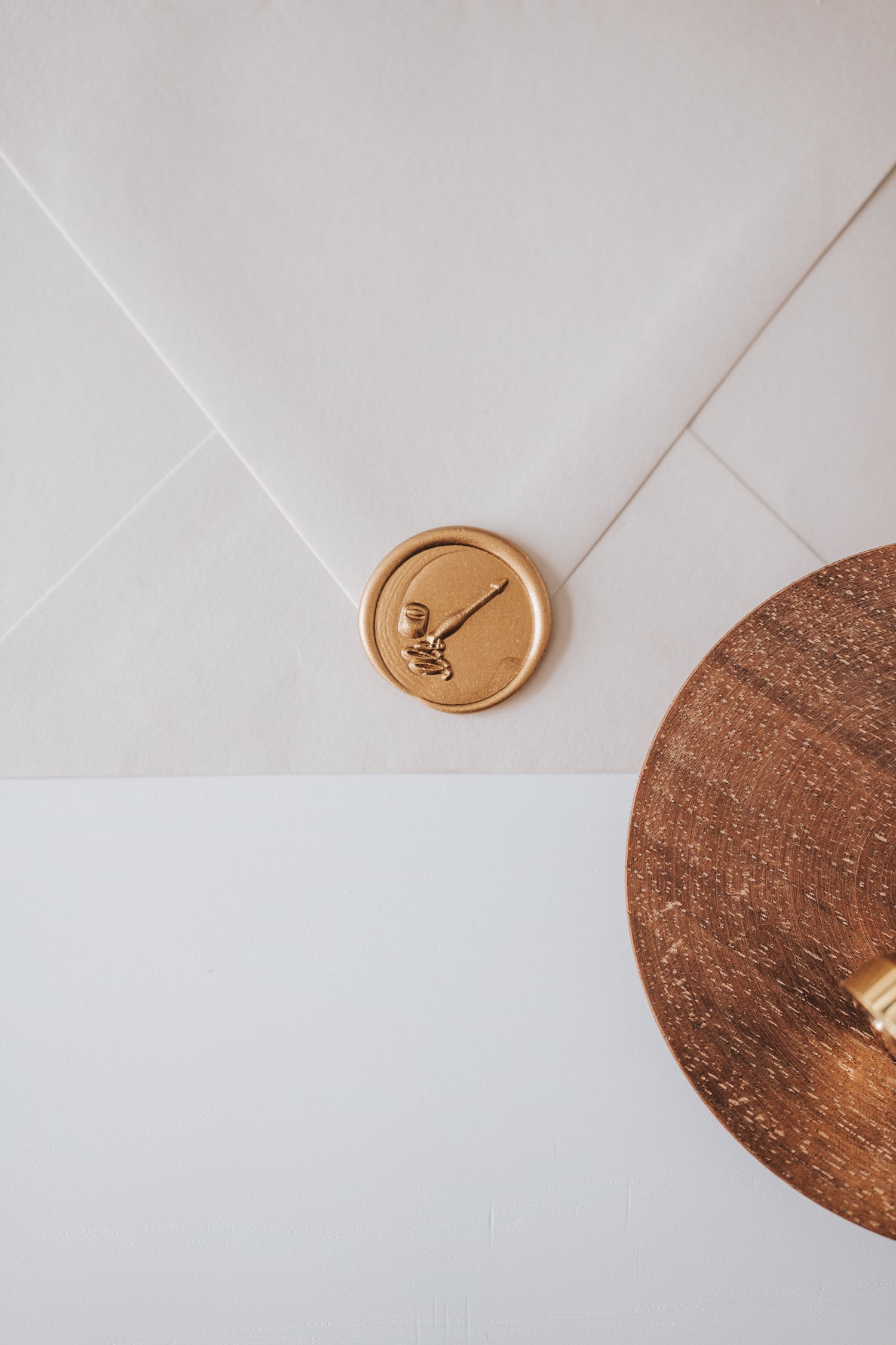 A beige envelope featuring a golden wax seal with a calligraphy penholder and ink jar design