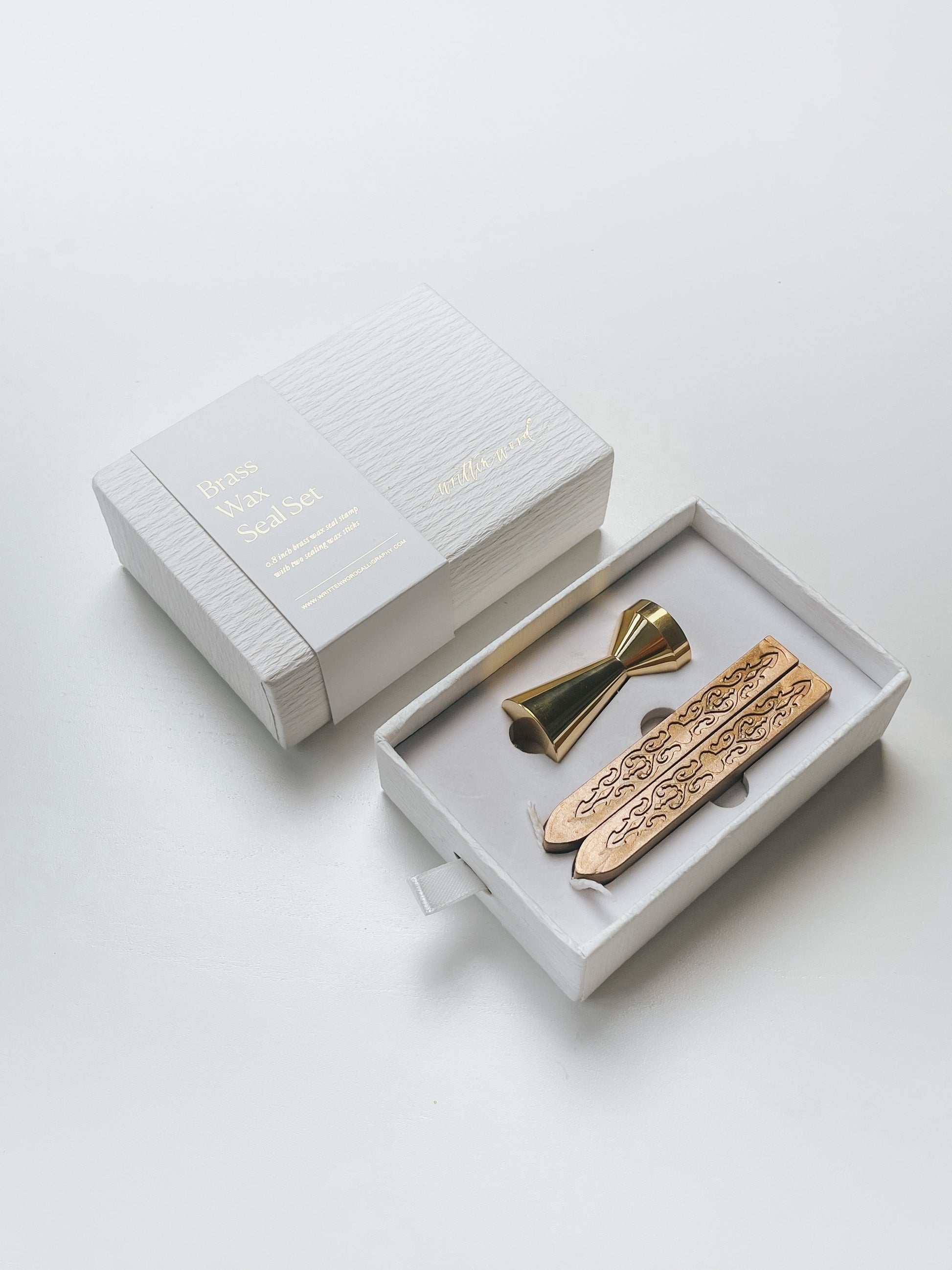Elegant brass wax seal set with two gold wax sticks in luxury packaging, styled elegantly on a white surface