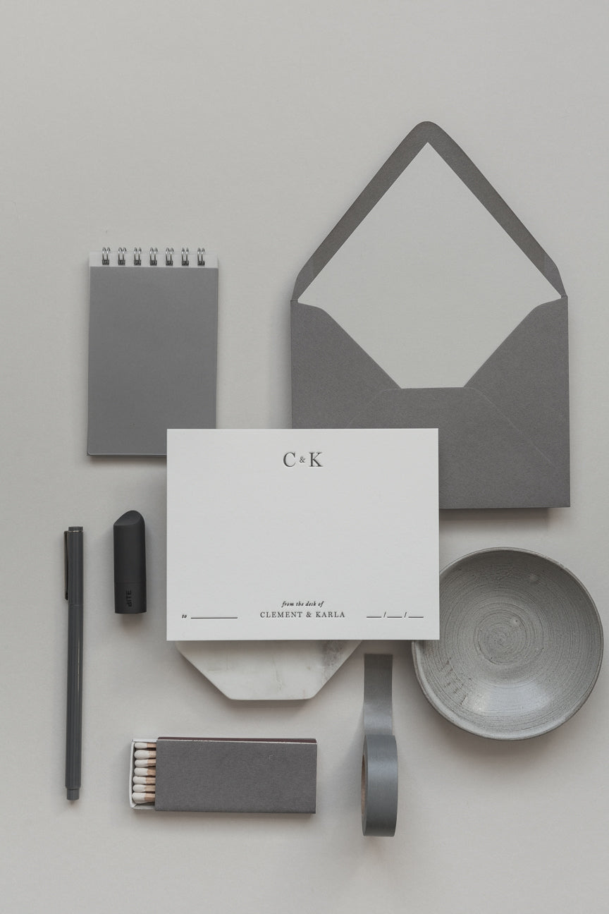 Neutral grey personalized stationery set with envelope, card, pen, matches and minimalist desk styling