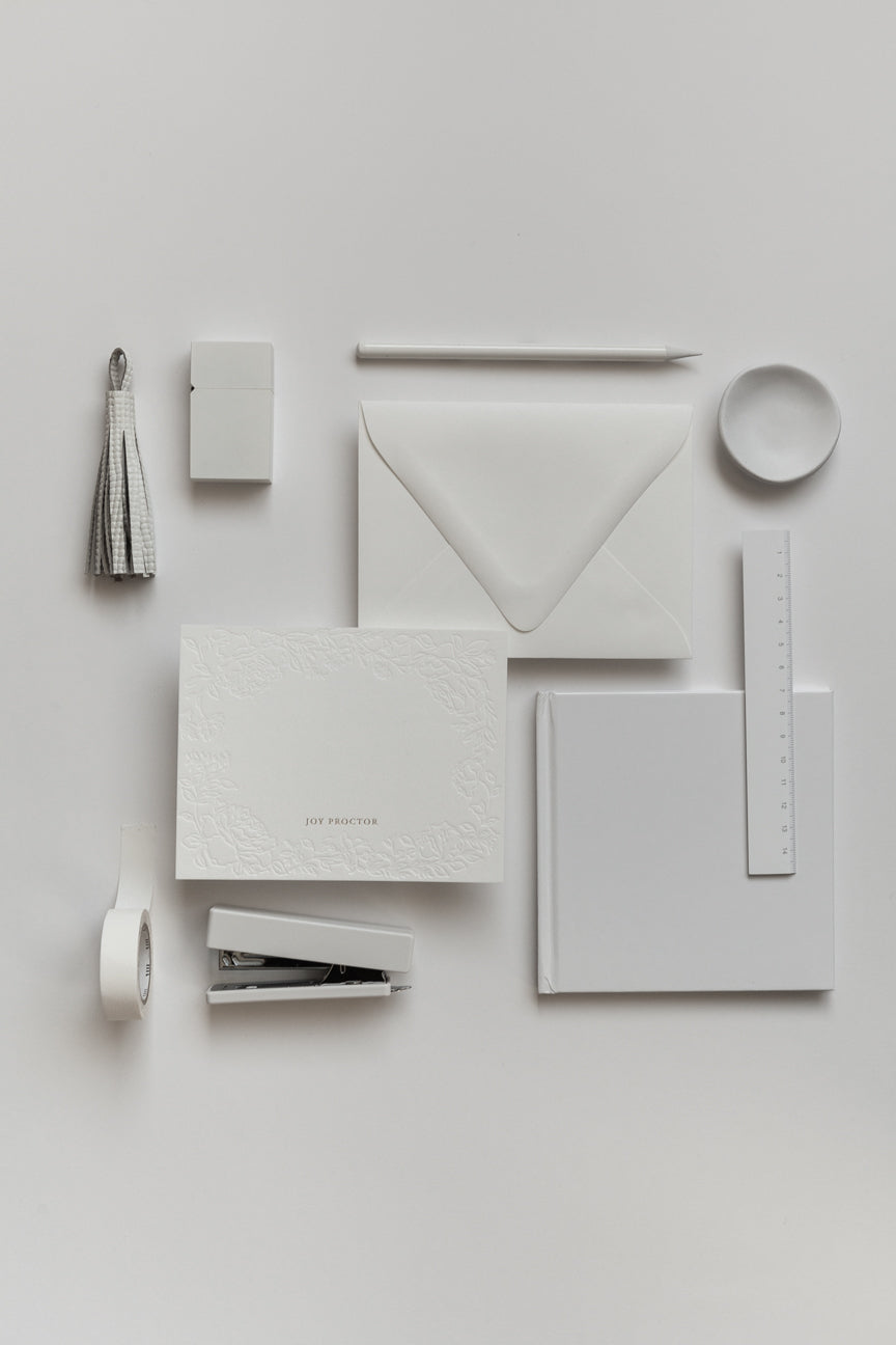 Flat lay of personalized stationery set with envelope, rings, and gold accents