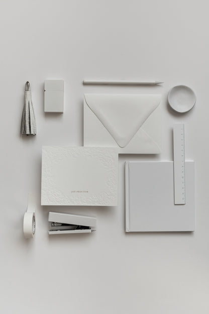 Flat lay of personalized stationery set with envelope, rings, and gold accents