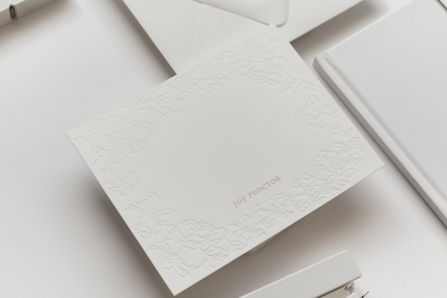 Embossed floral stationery card with gold name personalization on textured white paper