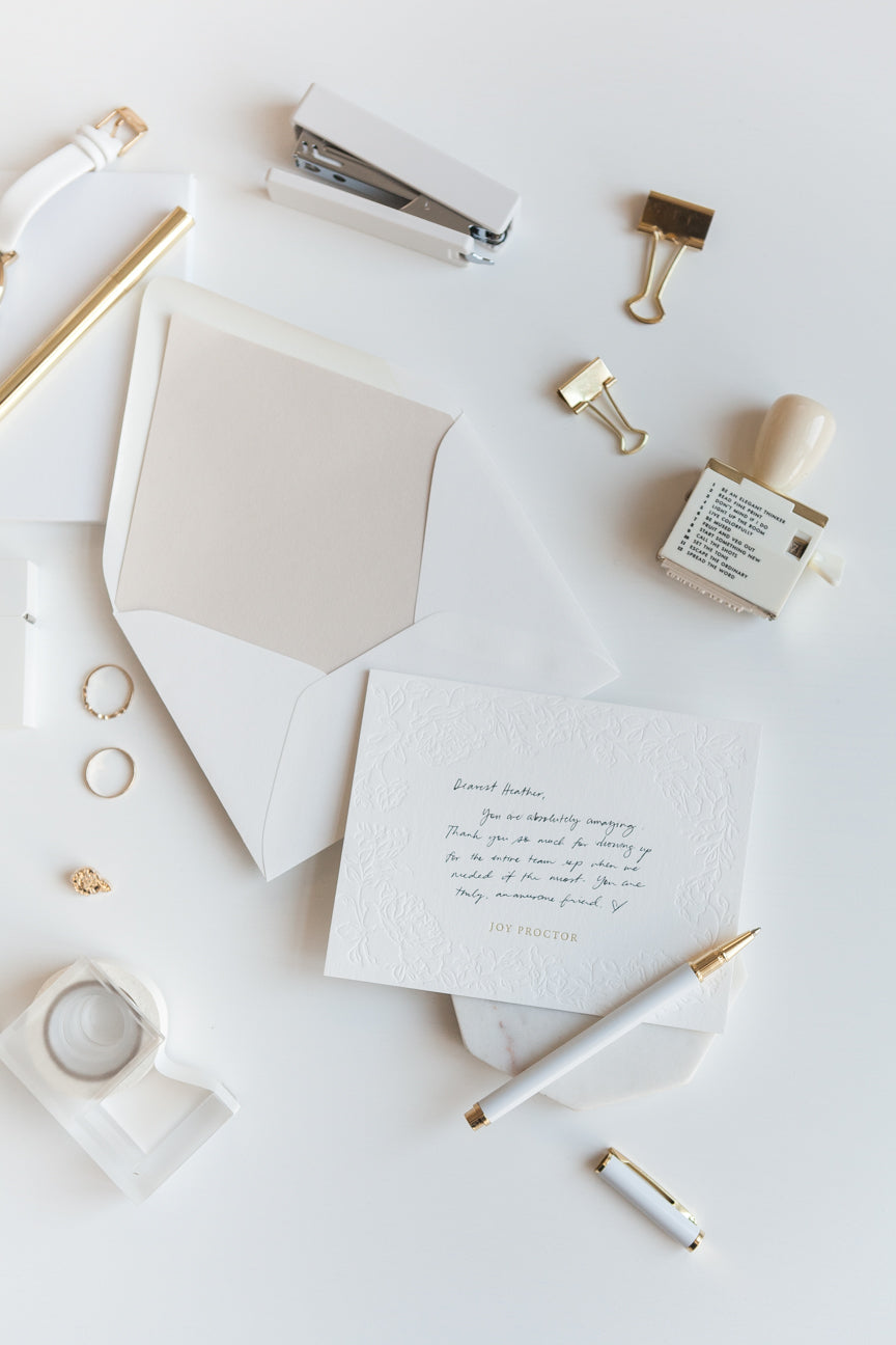 Handwritten note on embossed floral stationery card with gold personalized name